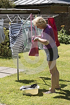 Woman taking pegs from a peg bag to hang washing