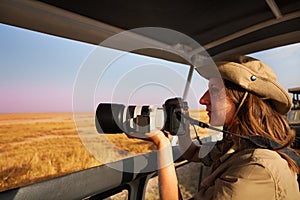 Woman taking photo aboard safari jeep at savannah