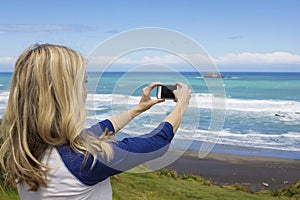 Woman taking a photo at the beach with her smartphone