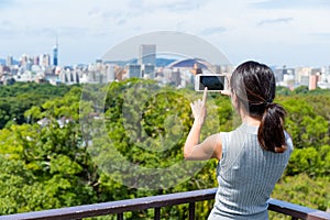 Woman taking photo on cellphone in Fukuoka city