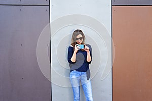 Woman taking photo with cellphone by the wall. Happy girl in cit