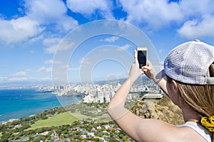 Woman Taking a photo of the city of Honolulu from high above the city at Diamond Head crater