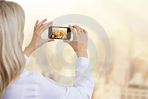 Woman taking photo of city in morning light