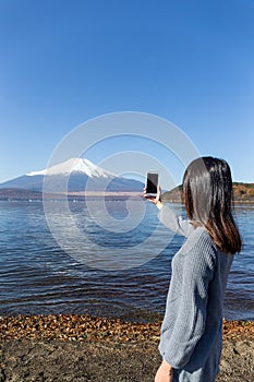 Woman taking photo with mobile phone on Fujisan