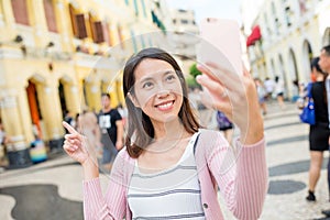 Woman taking photo by mobile phone in Macau