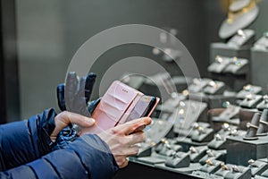 Woman taking photo with mobile phone of wedding rings in a jewellery shop window. Picture with shallow depth