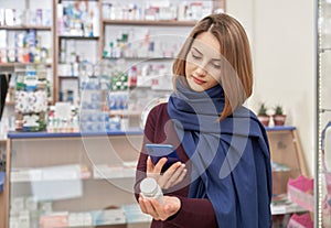 Woman taking photo of pills bottle in drugstore