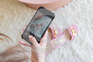 Woman taking photo of pink high heels shoes on beige rug with smartphone. Female blogger, influencer or stylist hand
