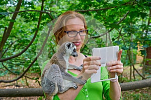 Woman taking photo selfie with ring tailed lemur