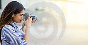 Woman taking a photo using professional camera. Young photographer, natural light. Copy space