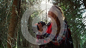 Woman taking photos on camera in forest. Tourist adjusting zoom on camera lens