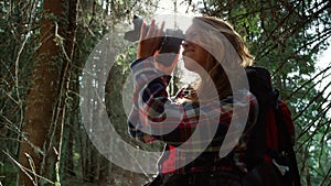 Woman taking photos on camera in forest. Tourist adjusting zoom on camera lens