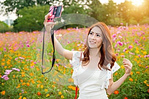 Woman taking photos at a cosmos flowers.