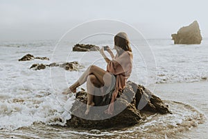 Woman taking photos with her phone on the beach