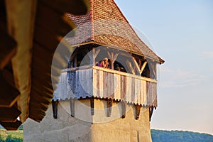 Woman taking photos up in a tower, in the fortified Evangelical church of Alma Vii, Transylvania, Romania, with warm sun setting.