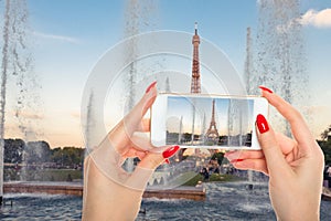 Woman taking a picture of Eiffel Tower with fountains