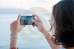 Woman taking pictures of beach, sea and resort at sunrise He used his phone to take high-angle shots. Travel concept and