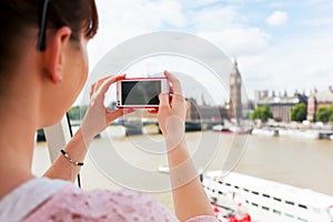 Woman taking pictures of Big Ben, London UK with smartphone, mobile.