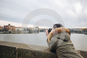 Woman is taking pictures on the Charles bridge in Prague. Young beautiful girl tourist stands on the Charles Bridge in Prague in