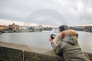 Woman is taking pictures on the Charles bridge in Prague. Young beautiful girl tourist stands on the Charles Bridge in Prague in