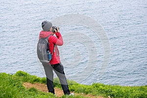 Woman taking pictures of the coast from a clifftop trail