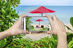 Woman Taking pictures on mobile smart phone show Red Umbrella on the beach