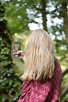 Woman taking pictures with smartphone in the forest