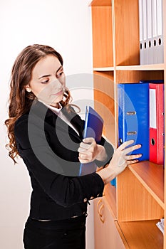 Woman taking a red folder from shelf