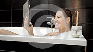 Woman taking a relaxing bath while having a video call on her tablet computer. Balance between modern technology and personal well