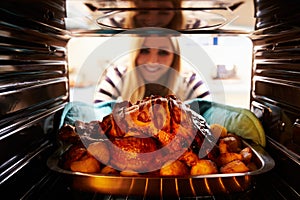 Woman Taking Roast Turkey Out Of The Oven
