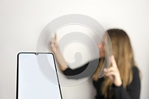 Woman taking a selfie in blurred background.Blank screen smartphone in foreground.People lifestyle , social networks and online