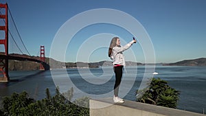 Woman taking selfie with Golden Gate Bridge