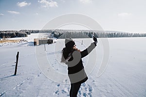 Woman taking a selfie of her surrounded by a scenic winter scenery