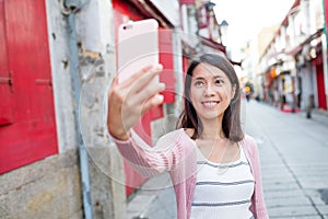 Woman taking selfie by mobile phone in Macau city photo