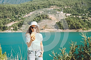 Woman taking selfie on mobile phone of mountains lake background. Traveler female having video chat on cellphone on the