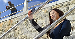 Woman taking selfie with mobile phone on stairs 4k