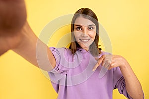 Woman taking selfie, point of view of photo, pointing finger down, recommend to subscribe her vlog.