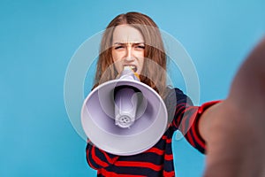 Woman taking selfie POV while making announcement in megaphone, screaming loudly.