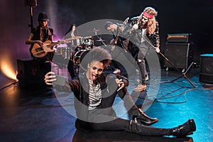 Woman taking selfie with rock and roll band performing concert on stage