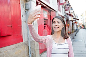 Woman taking selfie by smart phone in Rua da felicidade photo