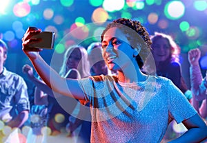 woman taking selfie with smartphone at nightclub