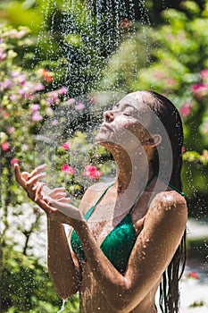 Woman taking shower outside in tropical garden. Luxury spa outdoors