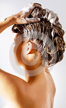 Woman taking a shower and shampooing her hair. Isolated on white.