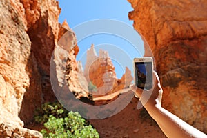 Woman taking smart phone picture of Rock Hoodoos in Bryce Canyon National Park photo