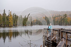 Woman taking smartphone photo of foggy landscape in Autumn
