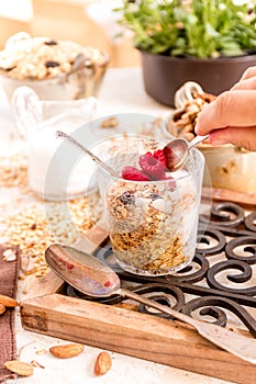 Woman is taking a spoon of Granola, yogurt, nuts and berries