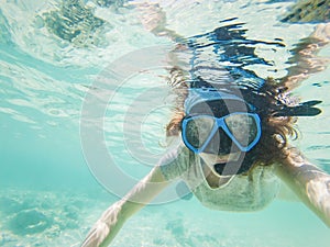 woman taking an underwater selfie while snorkeling in crystal clear tropical water