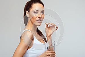 Woman Taking Vitamin Pils And Holding A Glass Of Fresh Water In Morning. Vitamin D, E, A Fish Oil Capsules,Omega-3. Diet.