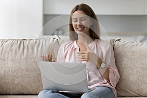 Woman talk through videoconference application sit on sofa with laptop