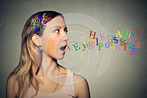 Woman talking alphabet letters in her head coming out of open mouth
